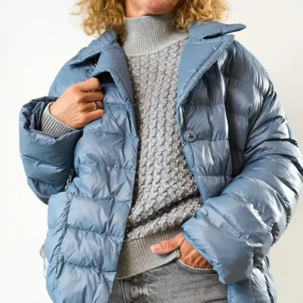 Dame draagt een lichtgrijze coltrui met een donzen blauwe jack erover