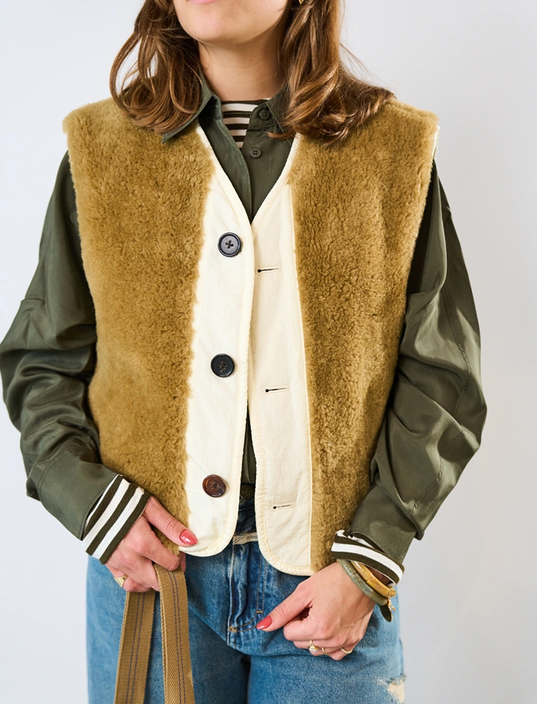 Een vrouw die een combinatie draagt ​​van een donkergroen jasje en een lichtgroen vest