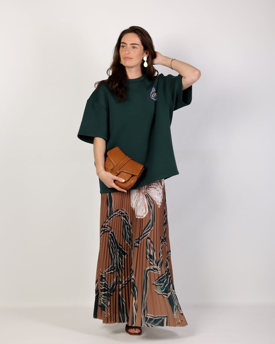 Dames outfit met groene top en lange plissé maxi rok in bruintinten