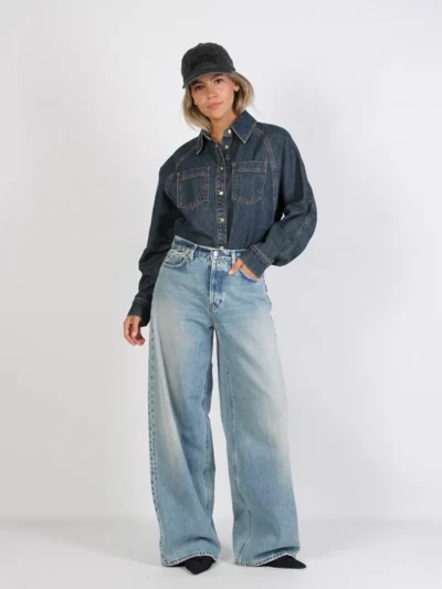 Donker denim jack met lichte wide leg jeans, pumps en pet.