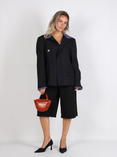 Model in donkerblauwe blazer met zwarte bermuda en Wandler tas