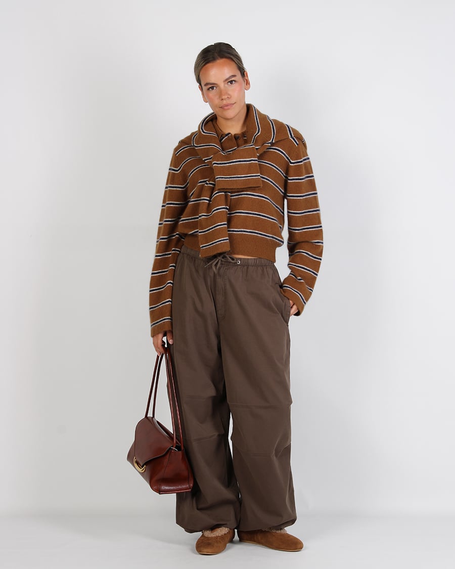 Bruine wide leg broek met gestreepte trui stylen 2 Frontale dameslook met bruin gestreepte trui, wijde broek en leren handtas