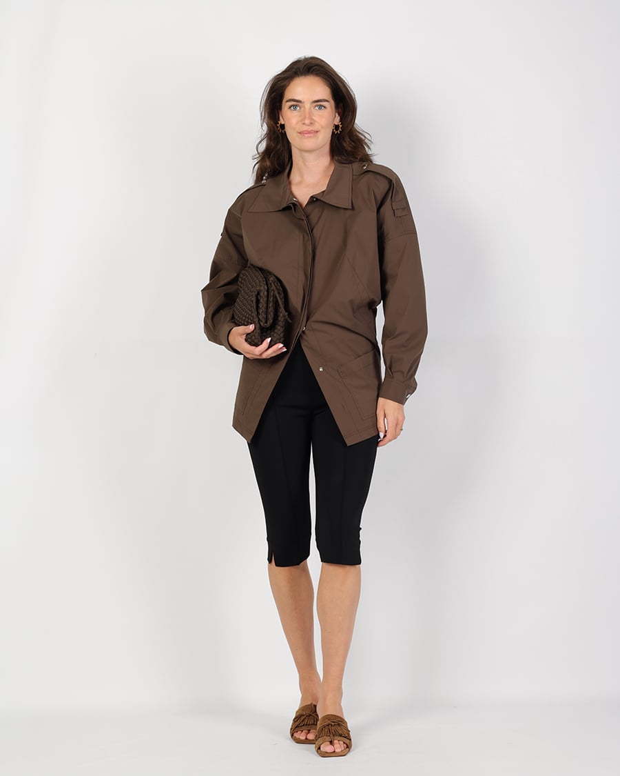 Bruine jas met zwarte capribroek combineren 1 Bruine utility-jas met zwarte capribroek, bruine clutch en gevlochten sandalen